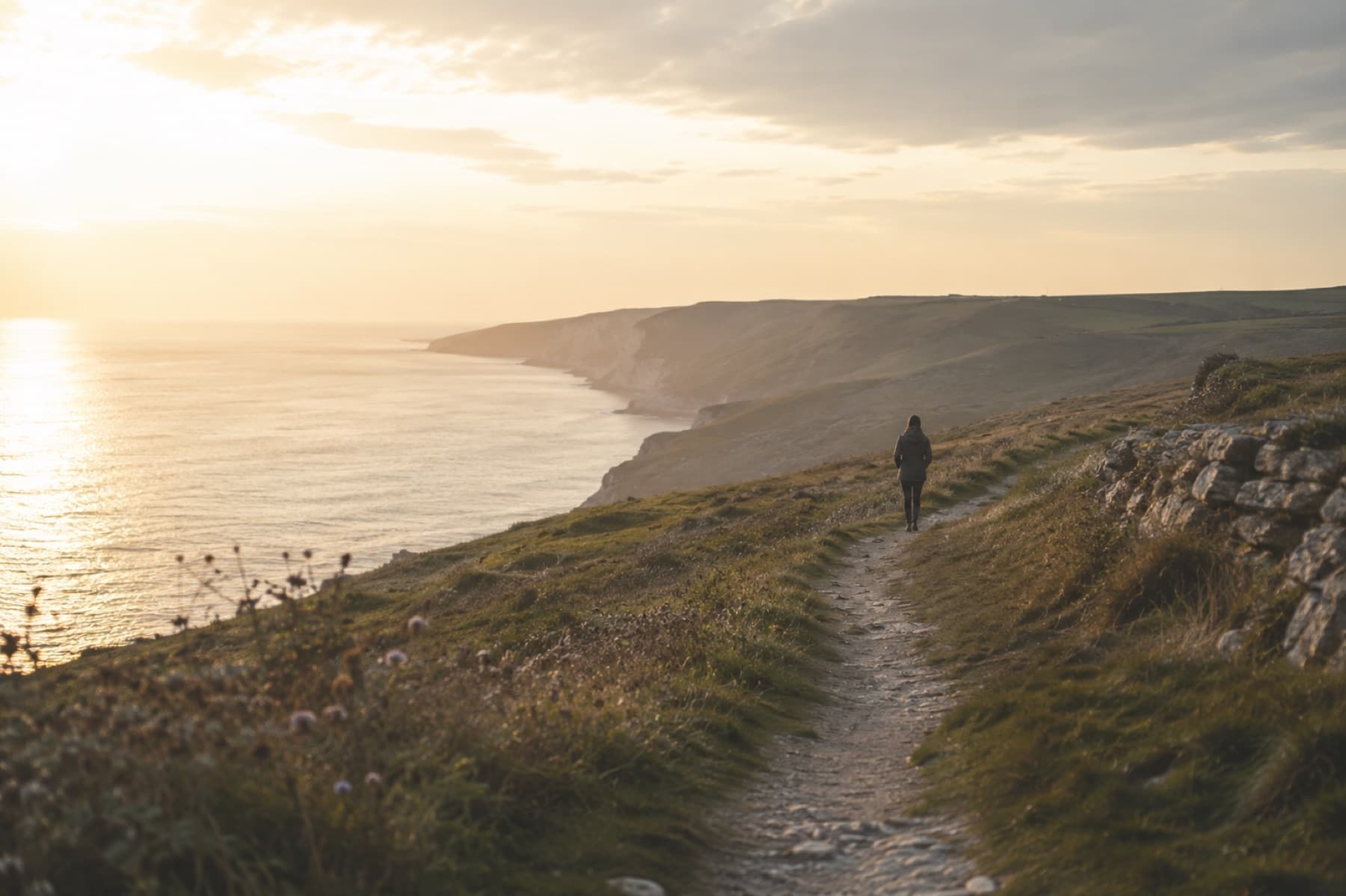 A person walking along a quiet coastal path after treatment