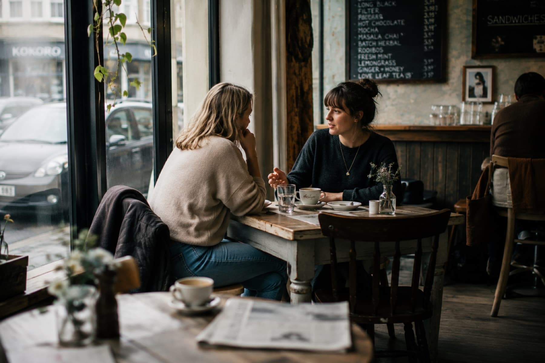 Two friends talking attentively over coffee in a quiet café